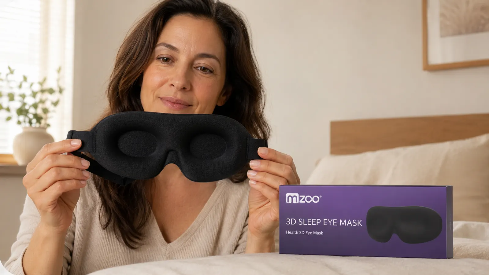 Close-up of the MZOO eye mask being held in one hand, showing the 3D molded eye cups and elastic strap